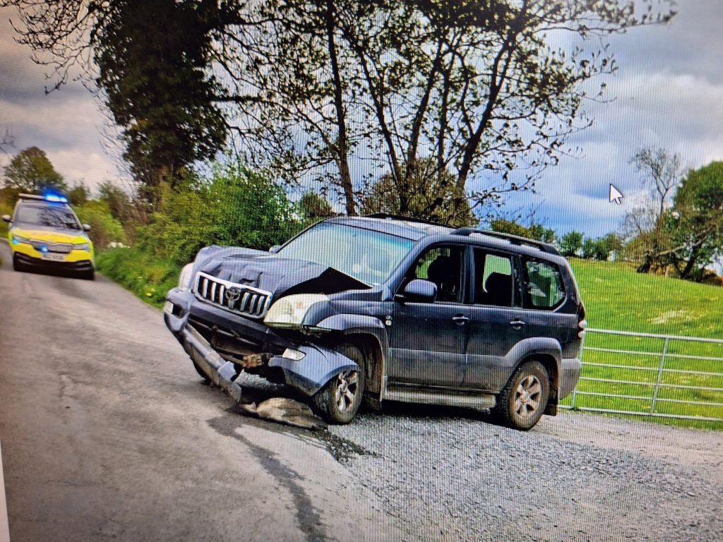 The stolen land cruiser parked on the side of a country road after it crashed. PSNI squad car in the background.